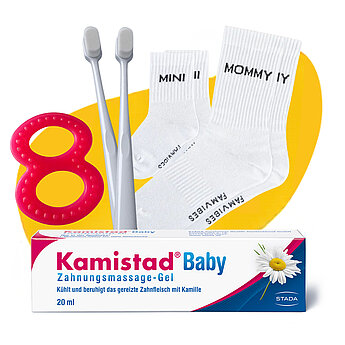 Eine Reihe von Babypflegeprodukten, darunter ein Lätzchen mit dem Logo "Zahnchampion", zwei Paar Socken mit der Aufschrift "MOMMY II" und "MOMMY III", zwei Zahnbürsten aus Holz und eine Tube "Kamistad Baby"-Zahnpasta.
