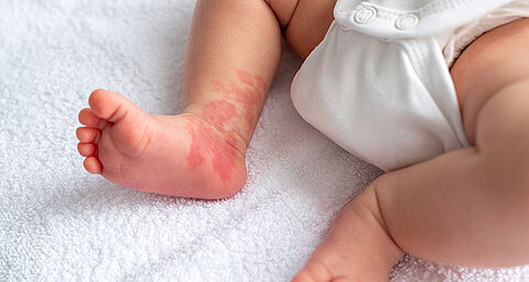 Fuß und Unterschenkel des Babys auf einem weißen Handtuch.