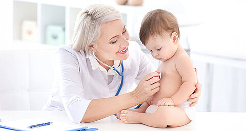 Eine medizinische Fachkraft, die ein Baby in einer klinischen Umgebung betreut.