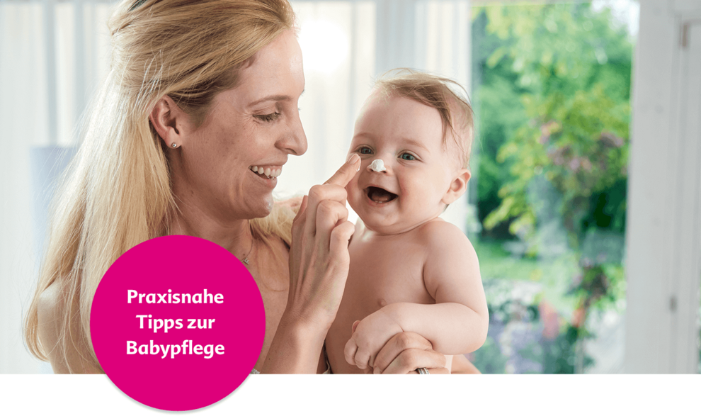 Ein freudiger Moment zwischen einer Mutter und ihrem Baby, wobei die Mutter etwas auf das Gesicht des Babys aufträgt.