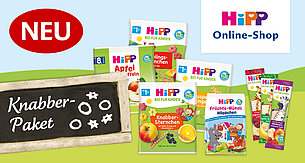 Eine Vielzahl von "Hipp"-Babynahrungsprodukten, die mit den jeweiligen Geschmacks- und Nährwertangaben beschriftet sind, begleitet von einem Kreideschild mit der Aufschrift "Knabber-Paket".