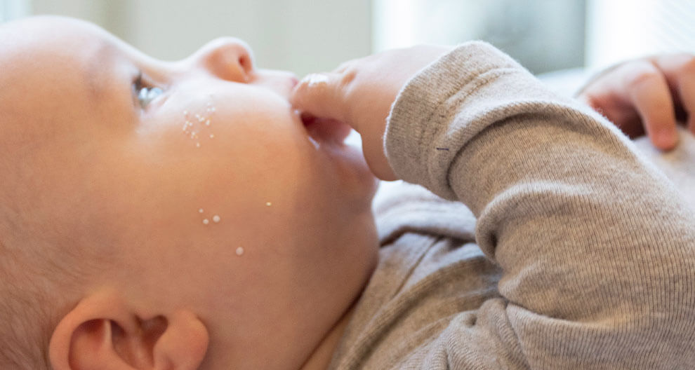 Baby mit kleinen weißen Körnchen im Gesicht.